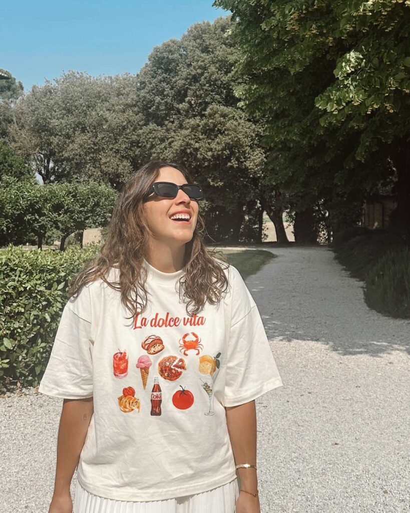 Chica con la camiseta La Dolce Vita de agua sal en un jardín